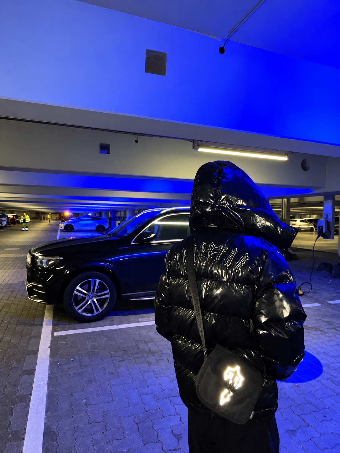 YGODOWN wearing a black hooded jacket in a blue-lit garage